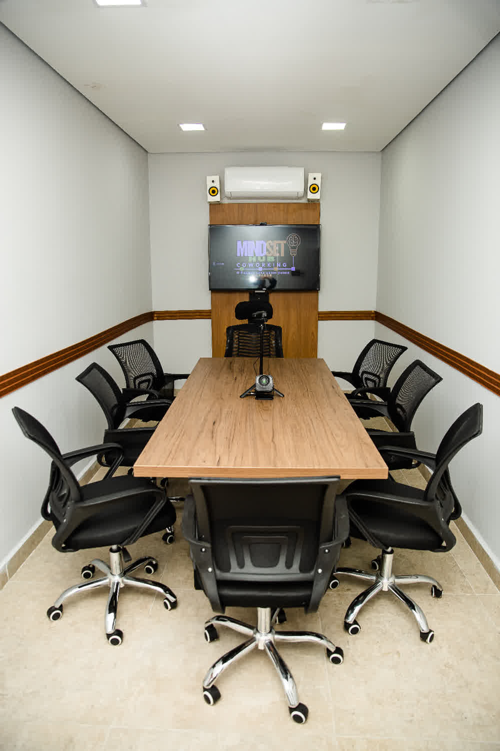 Sala de reunião com mesa de madeira e cadeiras executivas
