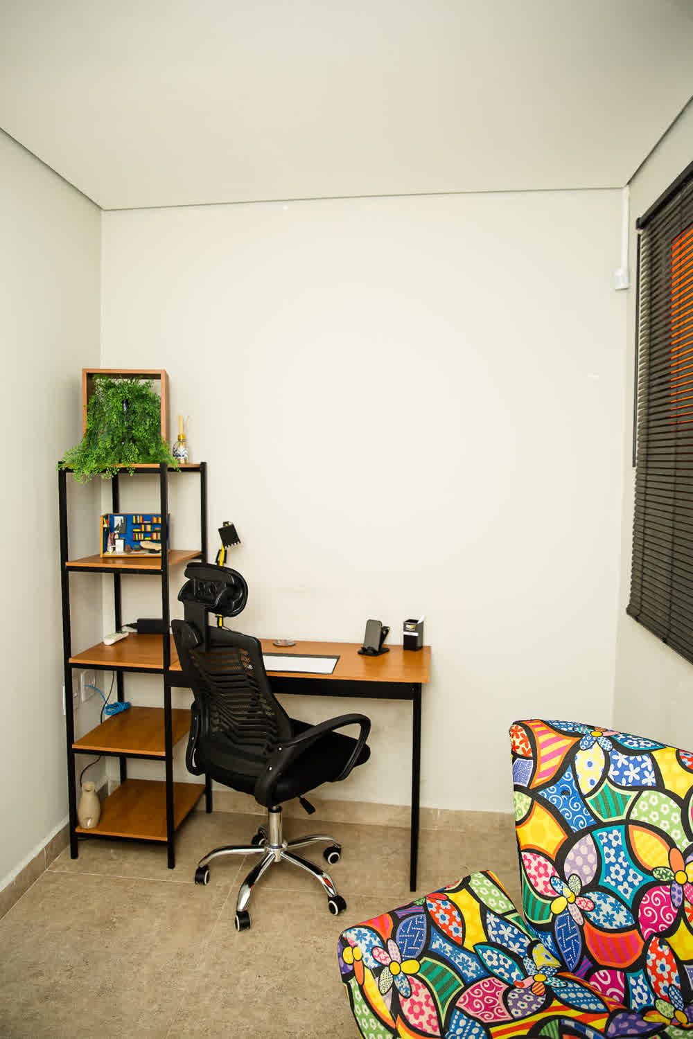 Escritório privativo com estante decorativa e cadeira ergonômica