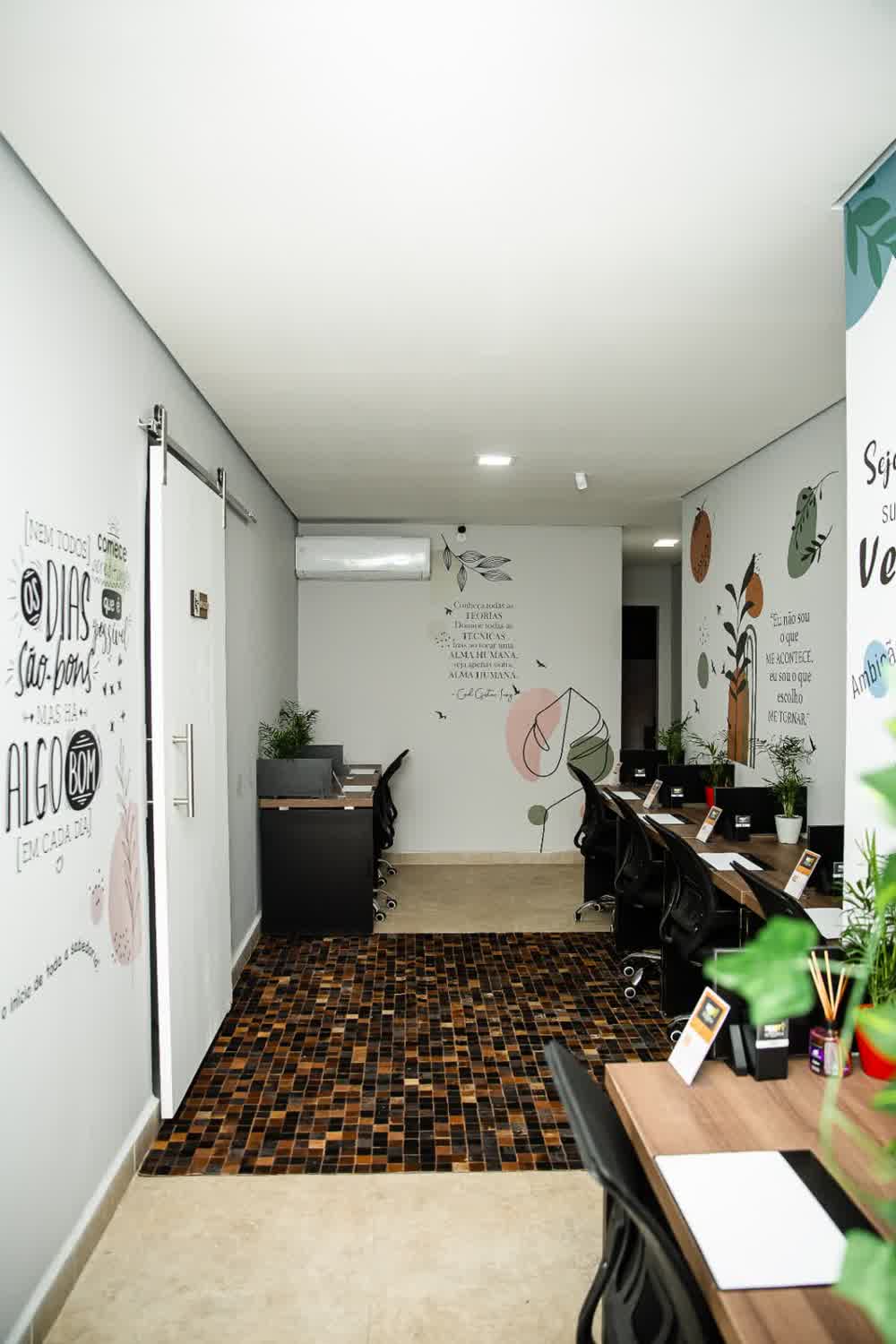 Visão geral do espaço coworking com piso mosaico e murais