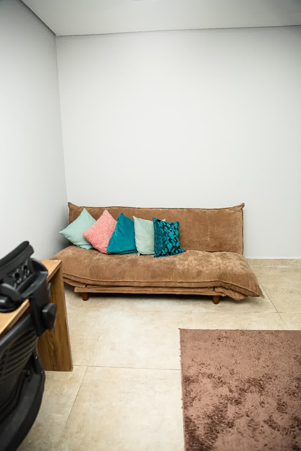 Espaço de descanso com sofá marrom e almofadas coloridas