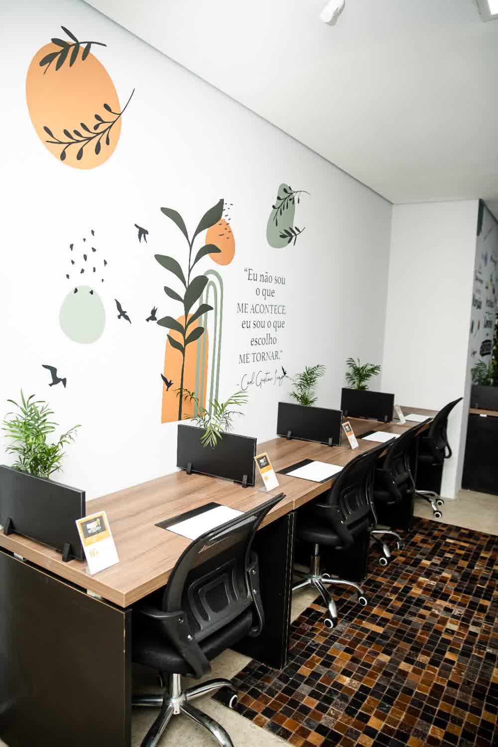Estações de coworking com mural inspiracional e cadeiras ergonômicas