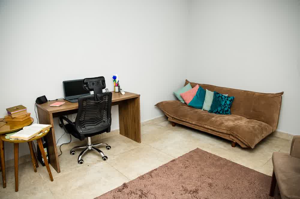 Sala de atendimento com sofá marrom, escrivaninha e cadeira