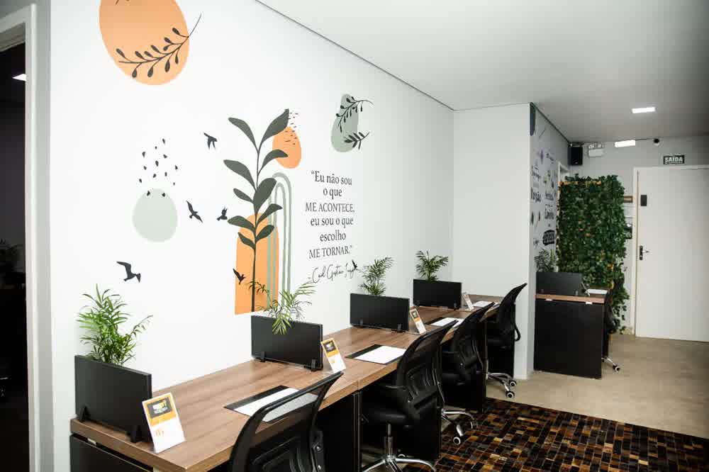 Vista ampla das estações de trabalho com mural artístico