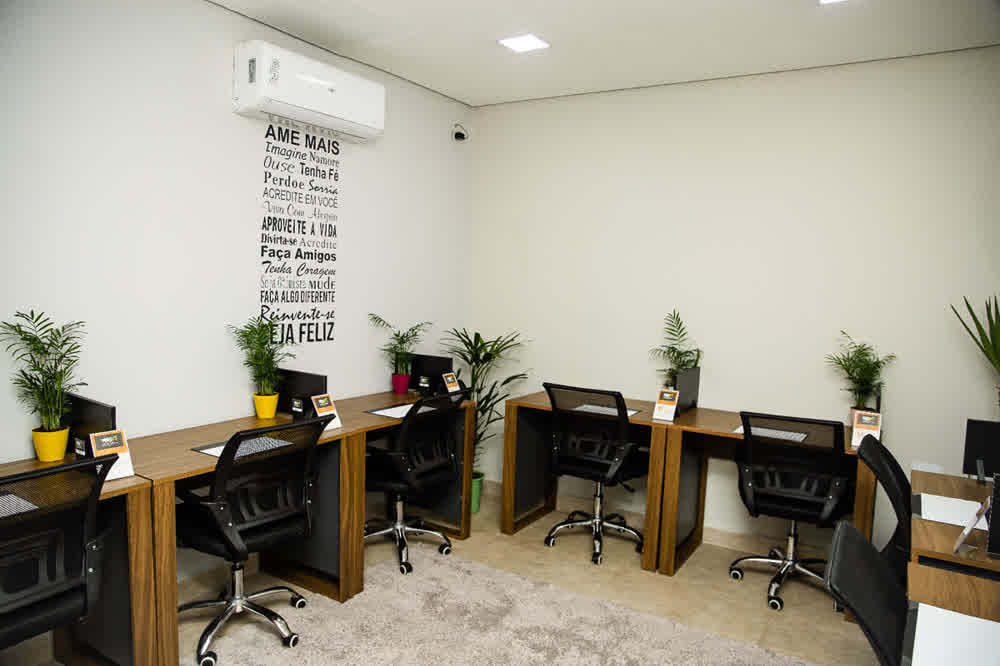 Sala coworking com estações individuais e mural motivacional