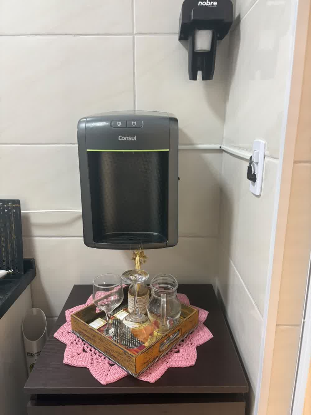 Cantinho do café com bebedouro, copos e bandeja decorativa