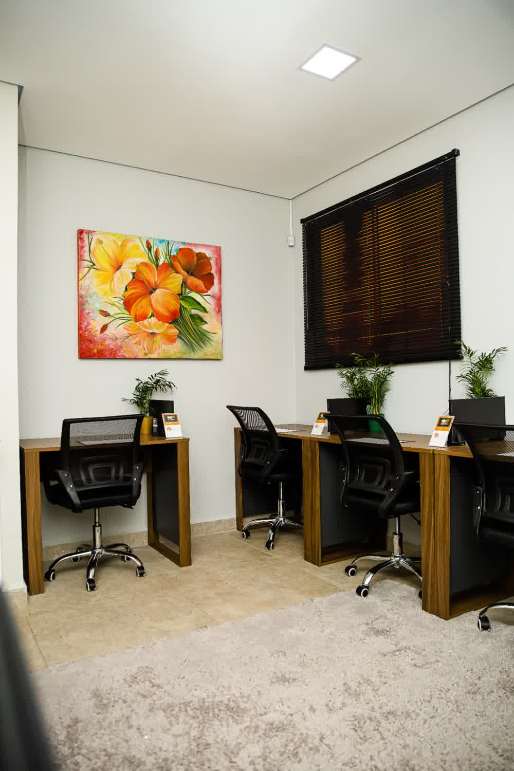 Sala privativa com quadro floral colorido e escrivaninhas
