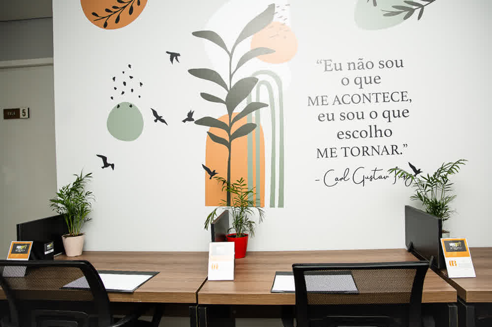 Estações de trabalho com mural artístico e citação de Carl Gustav Jung