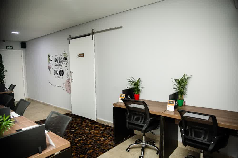 Sala de coworking com porta de correr e estações organizadas