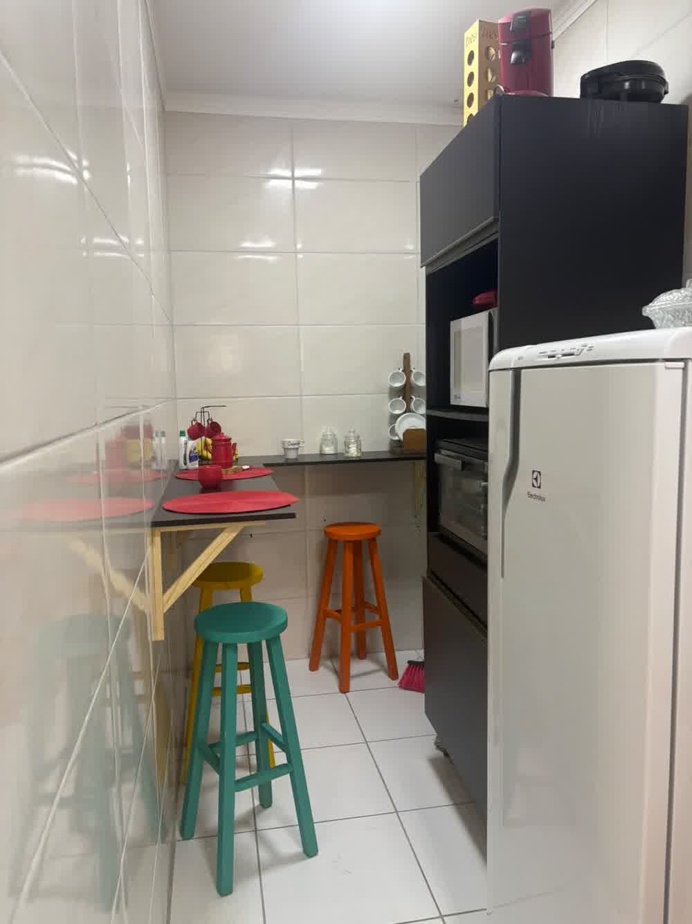 Copa equipada com geladeira, micro-ondas, forno e banquetas coloridas