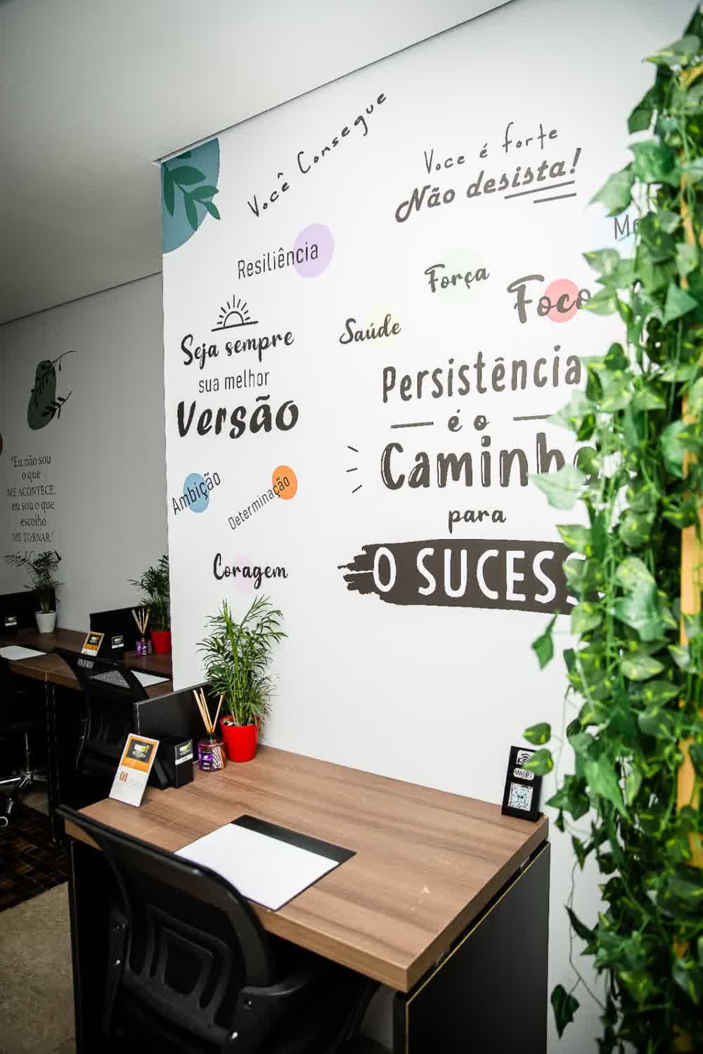 Detalhe do mural com frases inspiradoras e estação de trabalho